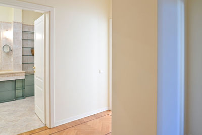 A corridor in the house, the entrance to a room with a white door and glass shelves.