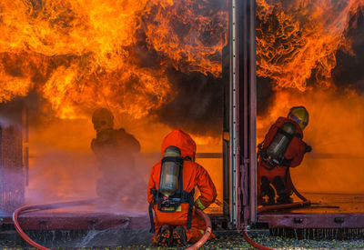 Rear view of firefighters spraying water