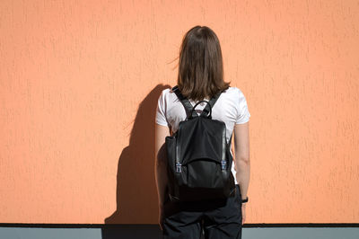 Rear view of woman standing against wall