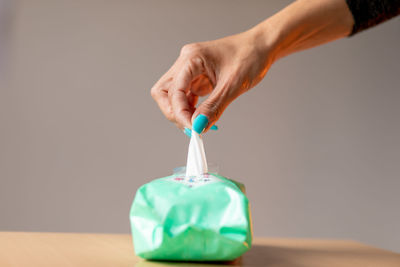 Midsection of woman holding bottle on table against wall