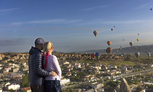 Rear view of couple looking at hot air baloons flying at cappadocia