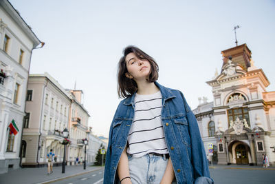 Low angle view of woman standing against buildings in city