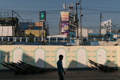 Man and buildings in city against sky during sunset