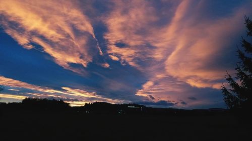 Silhouette landscape against dramatic sky during sunset