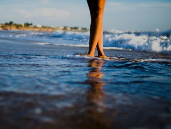 Low section of woman standing on shore at beach