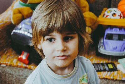 Close-up of boy by toys on chair at home