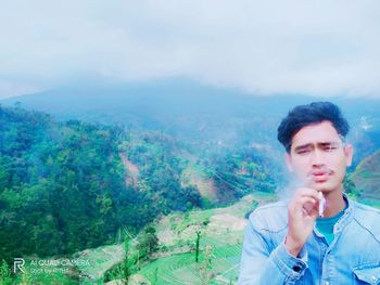 Portrait of young man looking at mountains against sky