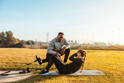 Woman exercising with instructor on land in sunny day