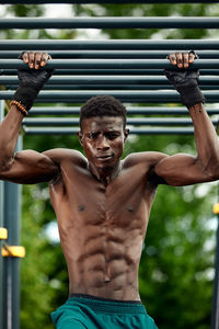 Portrait of shirtless young man exercising at park