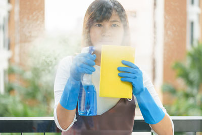 Portrait of teenage girl holding window