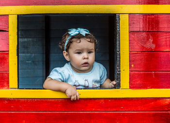 Close-up of cute baby girl against yellow wall