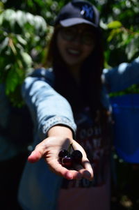 Smiling woman holding cherries outdoors