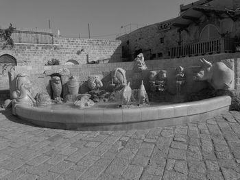 Statue by swimming pool in city against sky