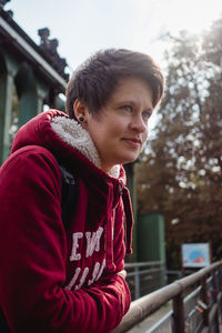 Woman looking away while standing by railing