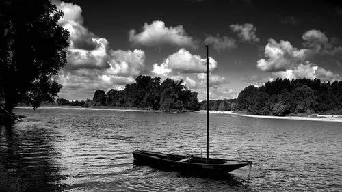 Boat moored on lake against sky