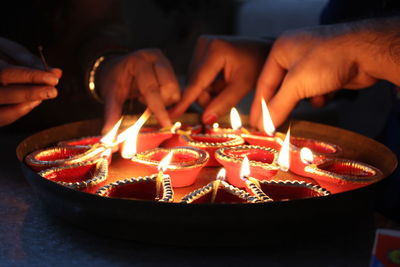 Close-up of hands holding diya at night