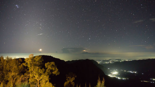 Scenic view of illuminated mountains against sky at night