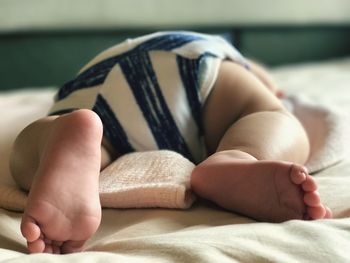 Low section of baby lying on bed