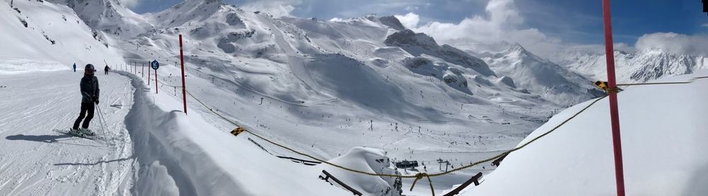 Panoramic view of people skiing on snowcapped mountain against sky