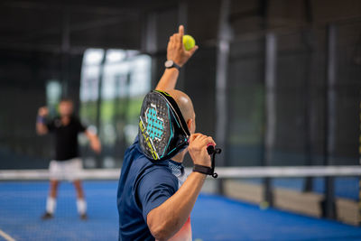 Monitor teaching padel class to man, his student - trainer teaches boy how to play padel 