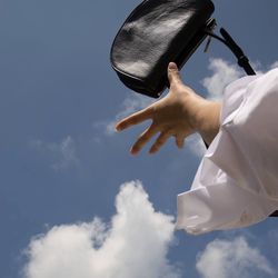 Low angle view of man holding hands against sky