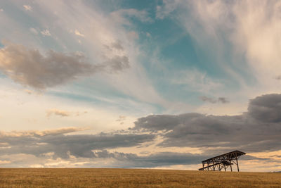 Scenic view of field and hangar against sky during sunset