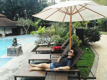 Woman relaxing on lounge chair by swimming pool