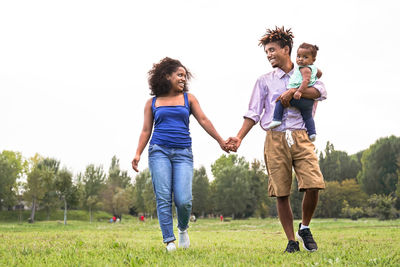 Full length of happy family at park against sky