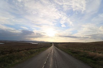 Road amidst field against sky