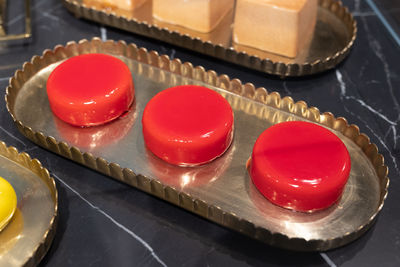 Three small cakes shaped round and covered with red icing on a tray.