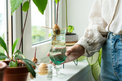 Midsection of man holding wineglass at home