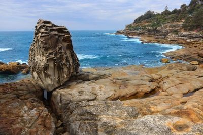 Rock formation on sea shore against sky