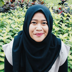 Portrait of smiling woman standing against plants