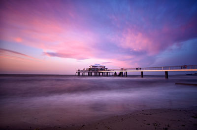 Pier over sea against sky at sunset