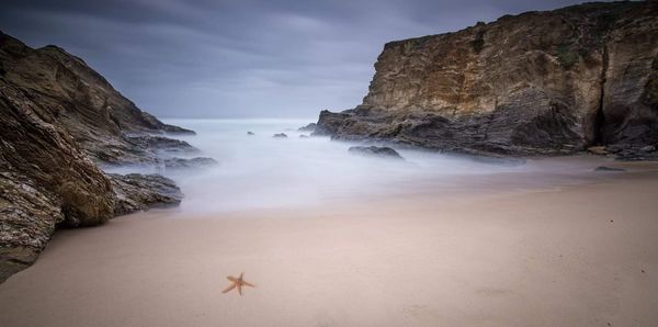 Scenic view of rocks on beach against sky