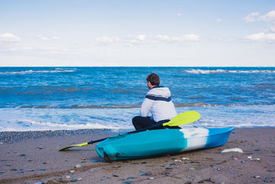 Man sitting on boat in sea against sky