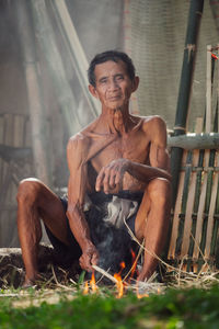 Portrait of shirtless man sitting on fire