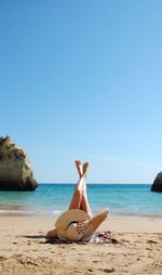 Woman sunbathing at beach against sky