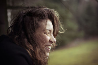 Beautiful wild free natural young woman looks out over field in wind