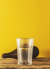 Close-up of beer glass on table against yellow background