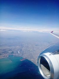 Aerial view of aircraft wing over landscape against sky