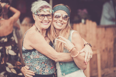 Portrait of cheerful woman embracing female friend outdoors