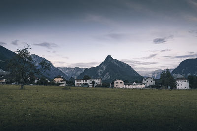 Houses on field by mountains against sky