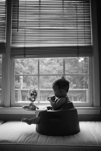 Cute girl sitting on window at home