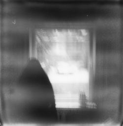 Rear view of silhouette person seen through glass window