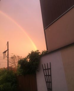 Low angle view of rainbow over building against sky