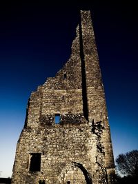 Low angle view of old ruin building against blue sky