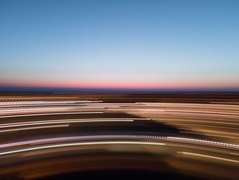 Light trails on road against sky during sunset