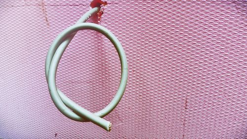 Close-up of cable forming letter q against pink wall