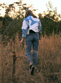 Rear view of woman walking on field